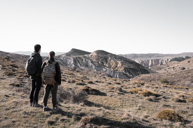 Two young male friends are watching a limestone formation in the distance during a hike