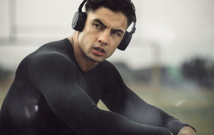 Close up of young athlete wearing headphones listening to music after workout