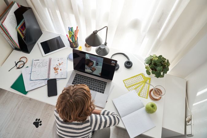 Unrecognizable boy video chatting on laptop while studying