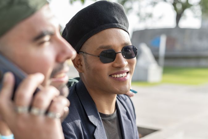 Gay male couple. One guy is looking at the camera while the other is talking on a smartphone