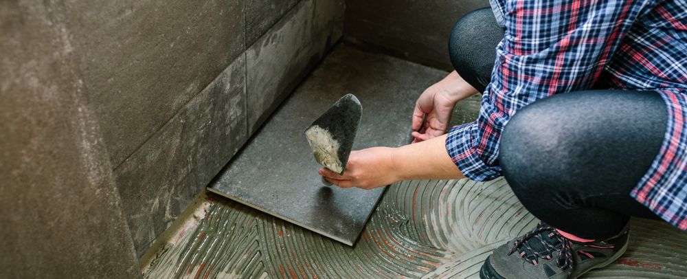 Female manual worker laying a new tile floor