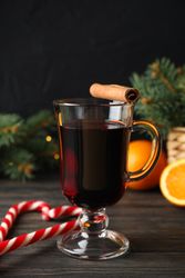 Glass of tasty mulled wine on decorated wooden background, space for text