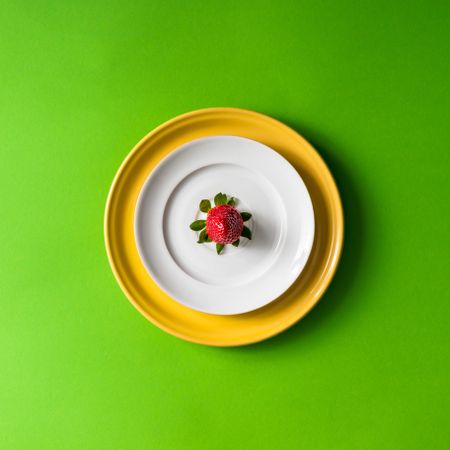 Strawberry on plate setup on green background