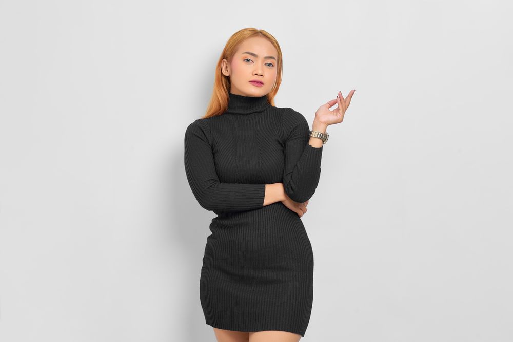 Sultry Asian woman with hand up red hair in dark dress in studio shoot with copy space
