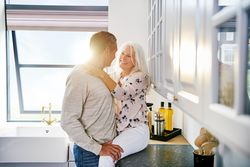 Older couple in kitchen with woman sitting on counter
