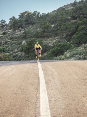 healthy man riding a bicycle on a mountain road in a sunny day