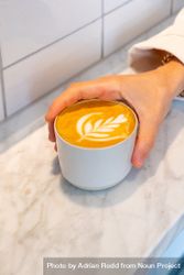 Hand holding cappuccino on marble table 4B1MM5