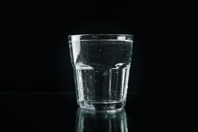 Single glass of water in dark room