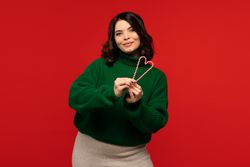 Woman in green sweater holding candy canes shaped like heart