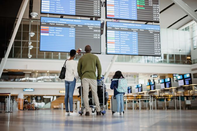 Parents with daughter waiting at airport and checking flight scheduled