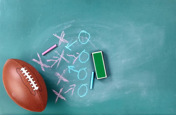 American football with play strategy on green chalkboard