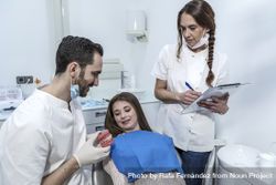 Young woman is sitting in dental chair in clinic with dentist is showing model of jaw 4OvZv5