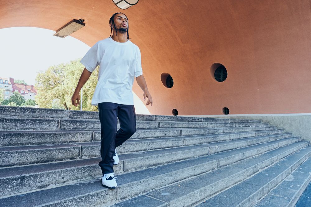 Trendy Black man walking down stairs near modern arch