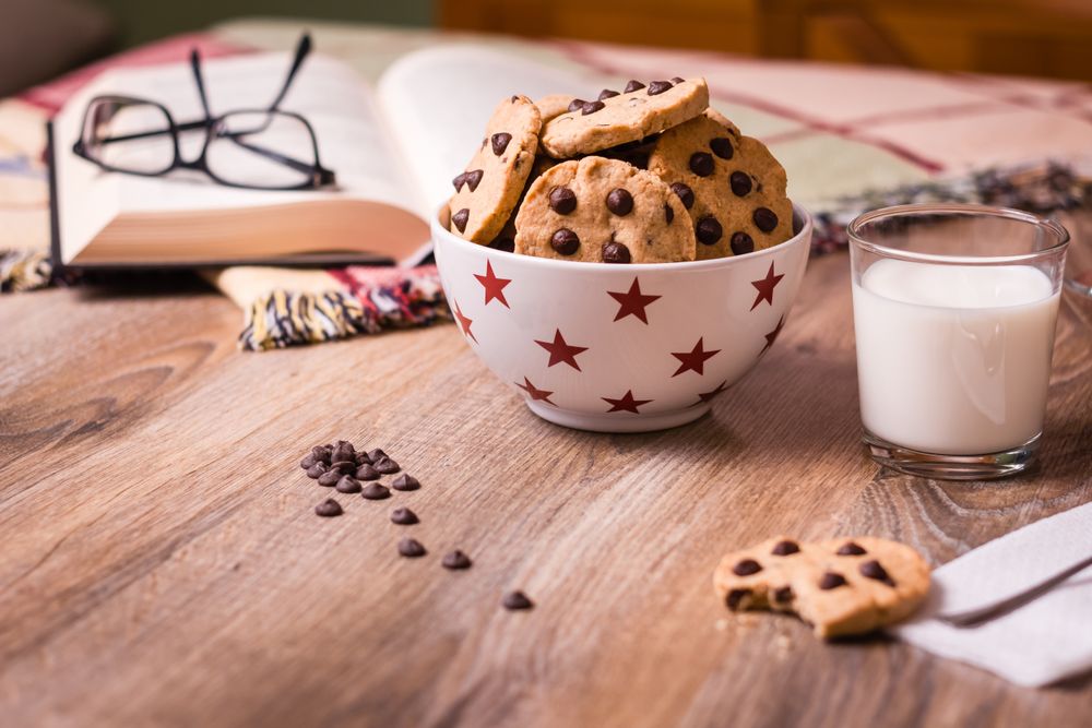 Chocolate chip cookies and milk on wood background