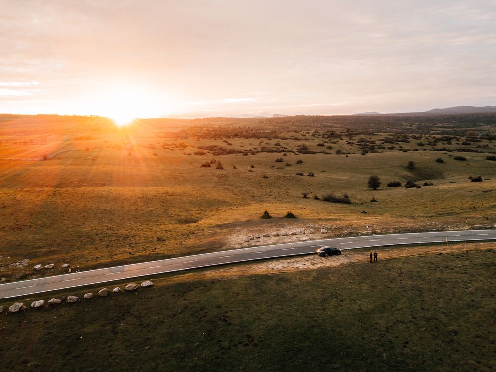 Bright sun setting over beautiful meadow and countryside road