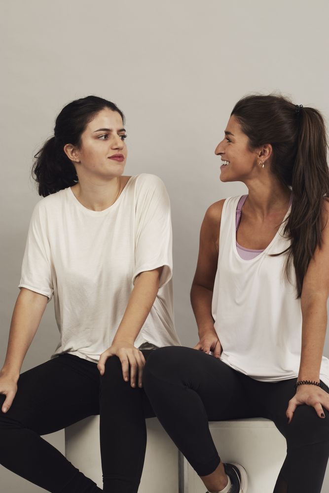 Happy young sportswomen resting after training in studio