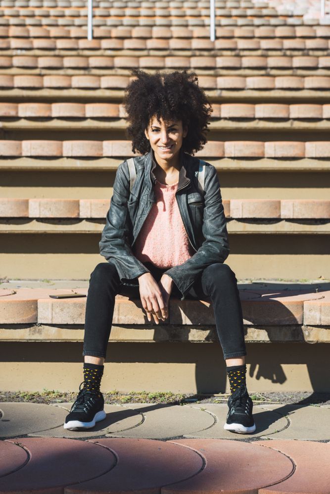 Woman with afro hair sitting on the steps of a stadium