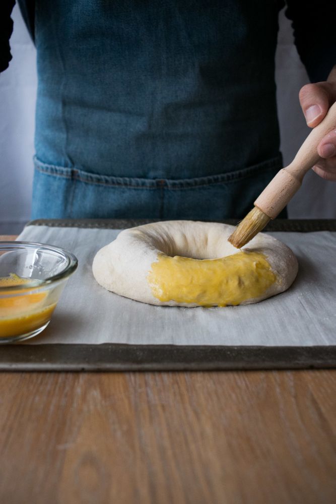 Crop cook smearing Rosca de Reyes with egg