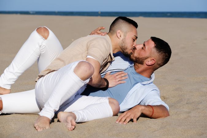 Affectionate gay couple relaxing on beach