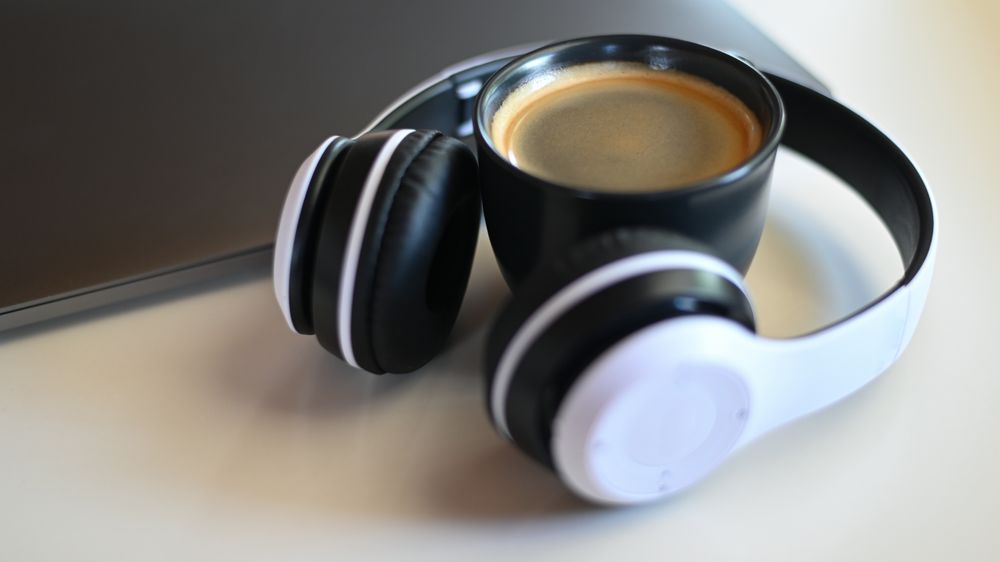 Coffee mug with laptop and headphone on placed on a table in a cafe