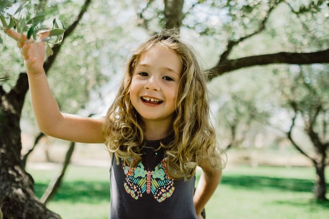 Smiling girl climbing tree in sunny day