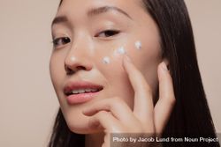 Close up of a young woman applying moisturizer to her face 439110