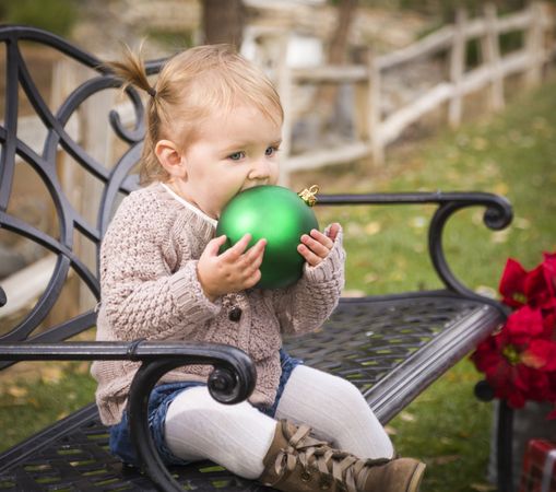 Toddler Child Sitting on Bench with Christmas Ornament Outside