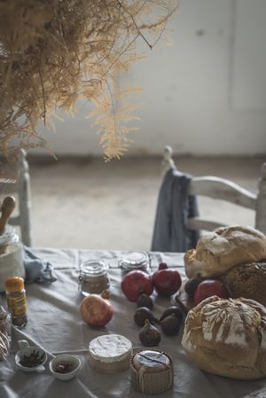 Fresh bread on served table and bunch of dry plant hanging on thread