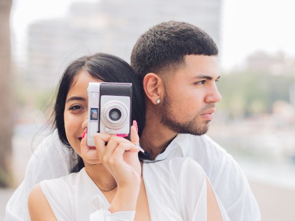 Woman taking photo and sitting with man on bench