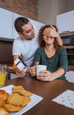 Man surprising woman with gift at breakfast