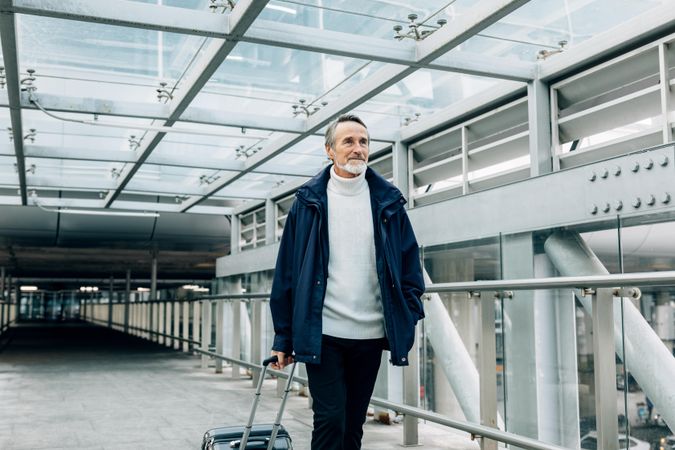 Older man leaving airport with suitcase