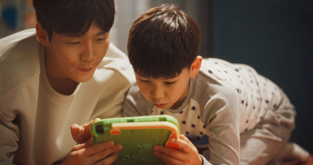 Portrait of a Handsome South Korean Father Playing with His Child in Children's Room.