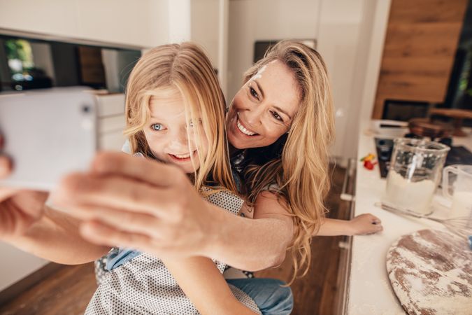 Close up of mother and daughter posing for selfie in kitchen