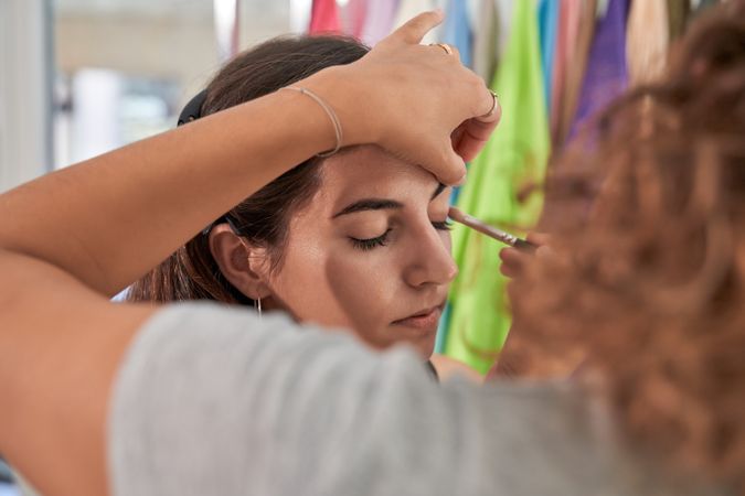 Unrecognizable woman applying eyeshadow on model