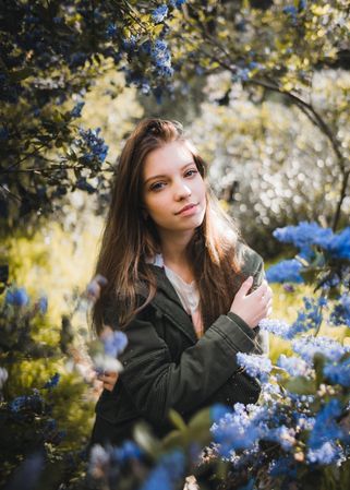 Portrait of young woman surrounded by blue flowers