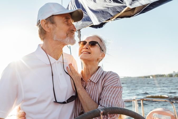 Happy older woman looking up at her husband steering a yacht