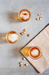 Top view of beer on wooden table with bottle opener and pistachios on grey background