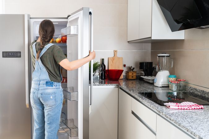 Crop woman taking fruit from fridge