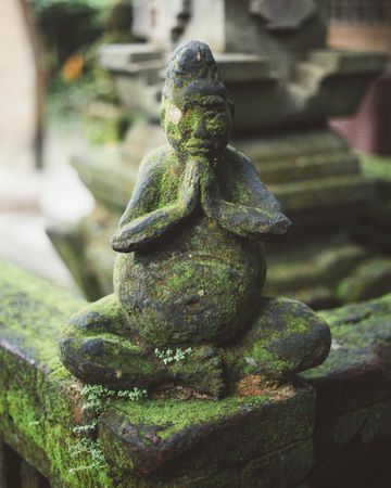 Mossy aged statue of monk on fence