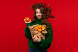 Young girl in green sweater holding oranges in paper bag