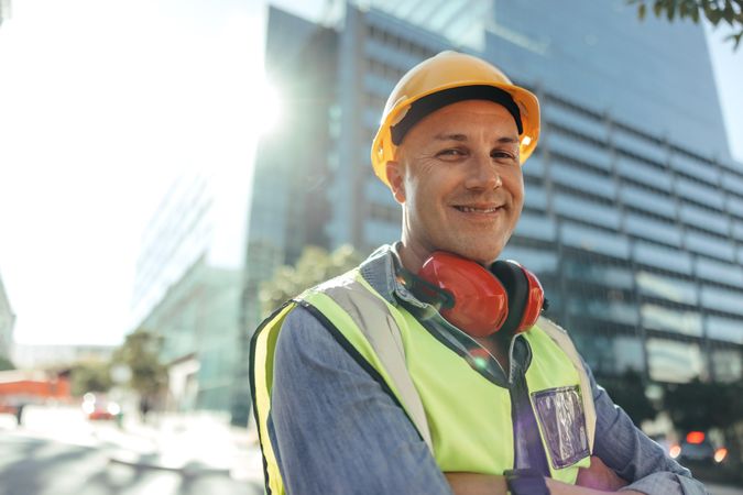 Confident construction worker standing in front of high rise buildings in his workwear
