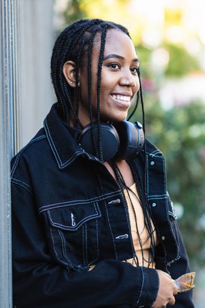 Black woman leaning on wall near park