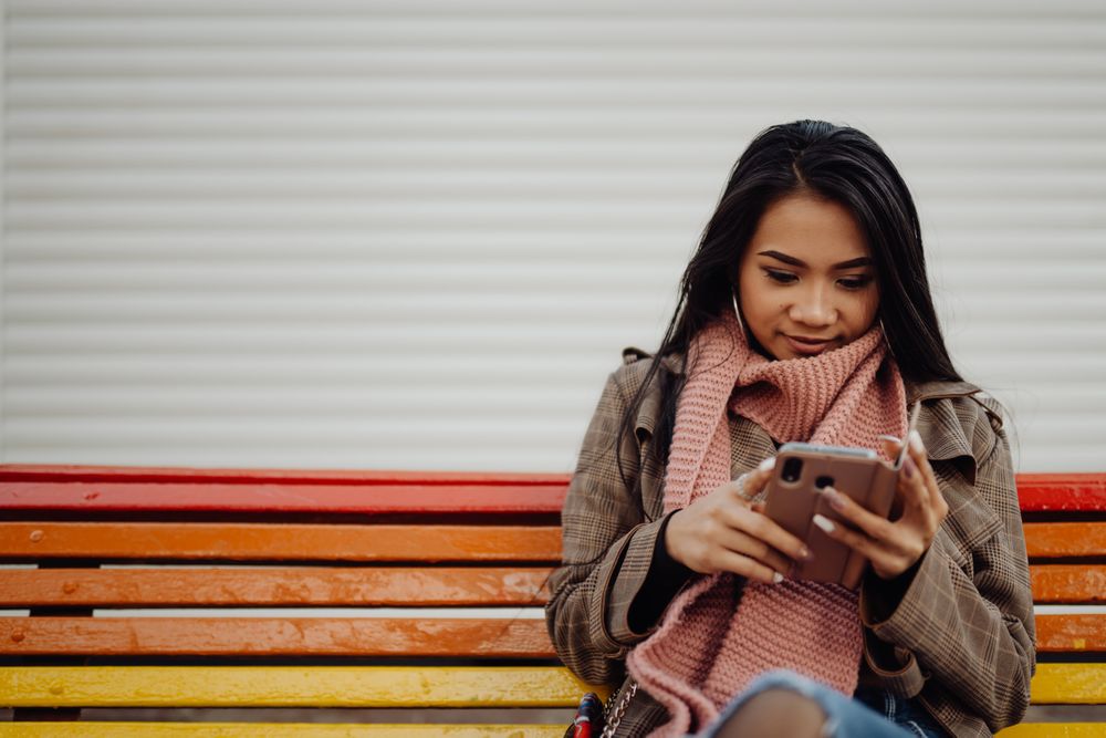 Asian using smartphone on bench
