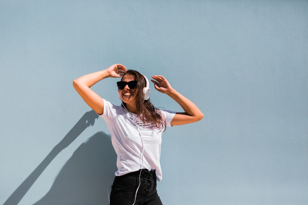 Cheerful casual woman in sunglasses standing on city street