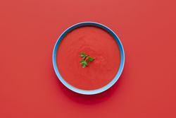 Tomato cream soup bowl, above view on a red background