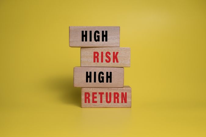 high risk high return words on wooden blocks isolated on yellow background