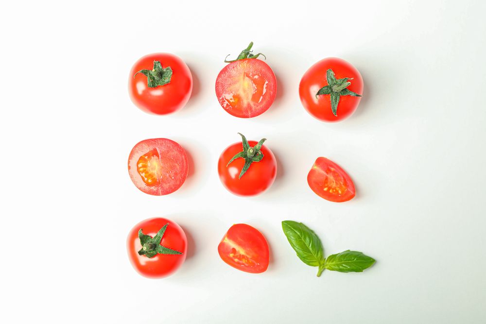 Flat lay composition with fresh cherry tomatoes and basil on blank background, space for text. Ripe vegetables