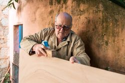 Mature man shaping wood with plane tool