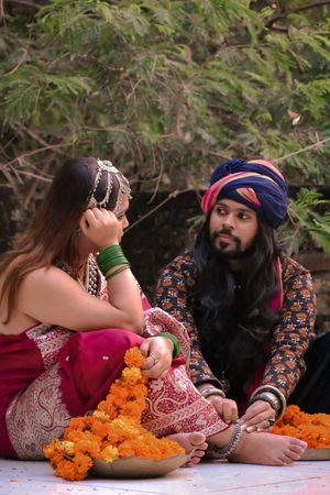 Indian couple in traditional outfit sitting on ground outdoor