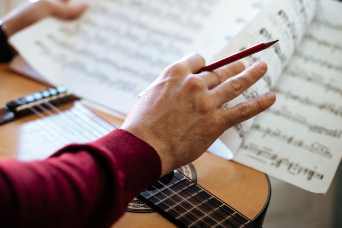 Man hands with sheet music playing guitar